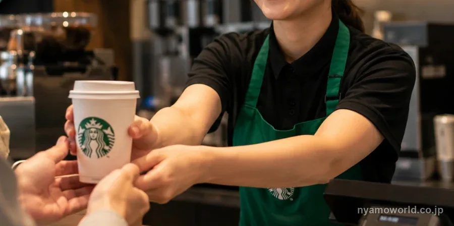 スターバックスの店員がカウンター越しにカップを手渡す様子
