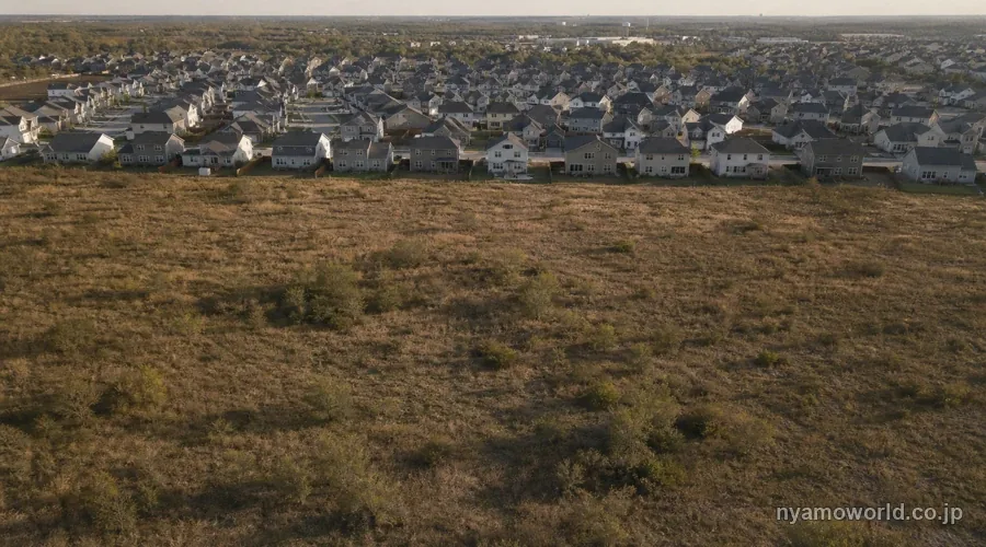 米国郊外の未開発の広い土地と、その奥に広がる新築戸建の住宅地との境目