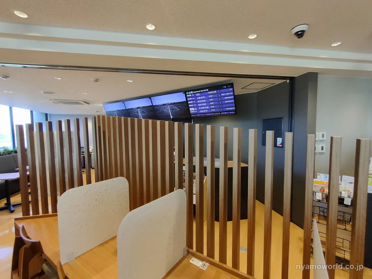 高知空港のカードラウンジ ブルースカイの内観。木の格子で仕切った席と出発便の案内表示