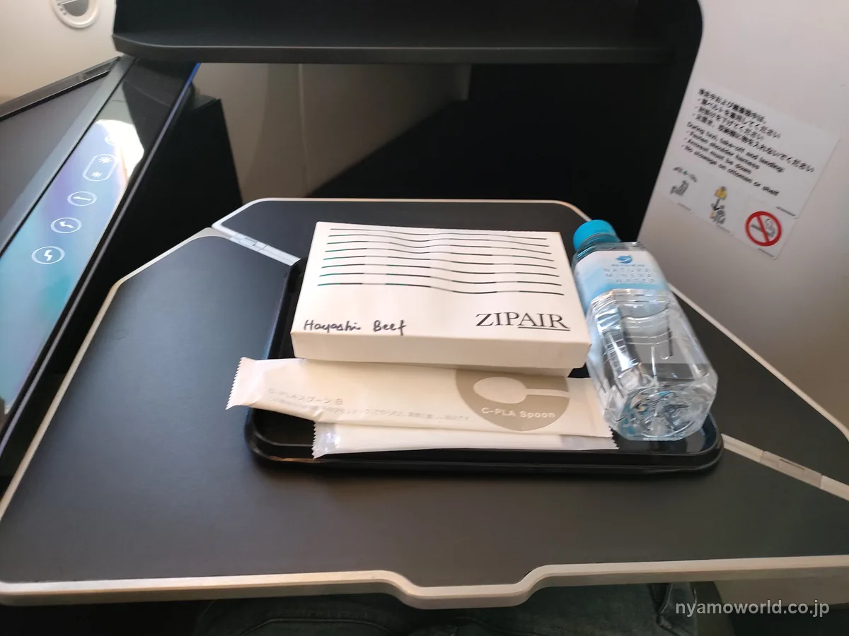 ZIPAIRのフルフラット席のテーブルに置いた事前予約の機内食と水